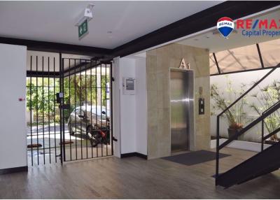 Spacious and modern building entrance with natural light, plants, and elevator access
