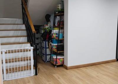 Modern staircase area with wooden floors and storage shelves