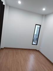 Empty bedroom with wooden flooring and a tall window