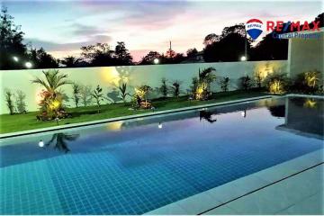 Well-maintained outdoor swimming pool with ambient lighting and landscaped garden