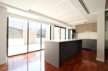 Modern kitchen with open plan design, featuring a large island, hardwood floors, and ample natural light