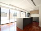 Modern kitchen with open plan design, featuring a large island, hardwood floors, and ample natural light