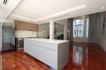 Modern kitchen with wooden floors, large island, and ample natural light