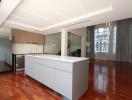 Modern kitchen with wooden floors, large island, and ample natural light