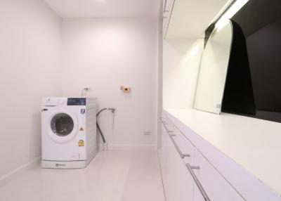 Modern laundry room with white washing machine and built-in cabinets