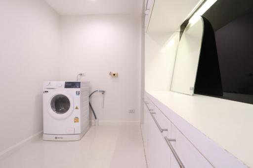 Modern laundry room with white washing machine and built-in cabinets
