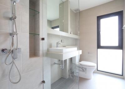 Bright modern bathroom with shower, sink, toilet, and window