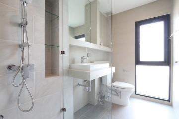 Bright modern bathroom with shower, sink, toilet, and window