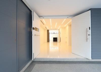 Brightly lit hallway leading to main living space with modern lighting and tiled floors