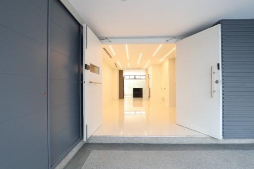 Brightly lit hallway leading to main living space with modern lighting and tiled floors