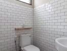 Clean white tiled bathroom with toilet and sink