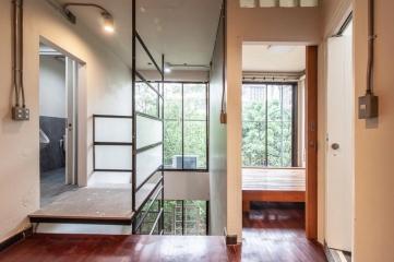 Modern hallway with stairs and large windows showing greenery outside