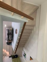 Modern staircase with wooden steps overlooking a contemporary kitchen downstairs