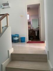 Hallway leading to a bathroom, showing stairway and tile flooring