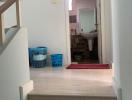 Hallway leading to a bathroom, showing stairway and tile flooring