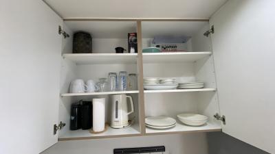 Open kitchen cupboard with shelves stocked with various dishes and kitchenware