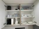 Open kitchen cupboard with shelves stocked with various dishes and kitchenware