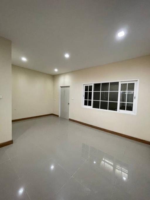 Bright and spacious empty room with glossy tiled floor, multiple ceiling lights, and large window
