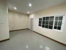 Spacious empty room with large windows and tiled flooring