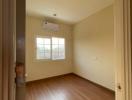 Spacious unfurnished bedroom with wooden flooring and air conditioning