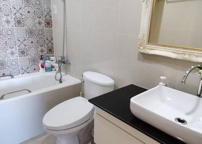 Modern bathroom with patterned wall tiles, bathtub, and a stylish sink