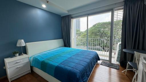 Cozy bedroom with a queen-sized bed, blue accent wall, and a balcony access