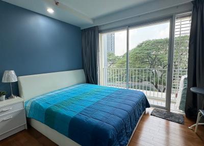 Cozy bedroom with a queen-sized bed, blue accent wall, and a balcony access