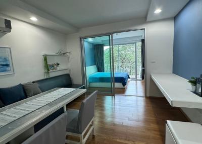 Bright bedroom with sliding door to balcony, wooden flooring, and white and blue decor
