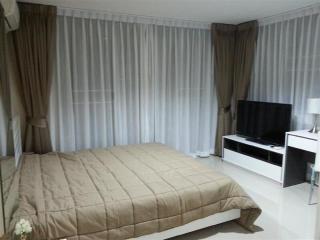 Modern bedroom with king-sized bed, floor-to-ceiling curtains and entertainment unit