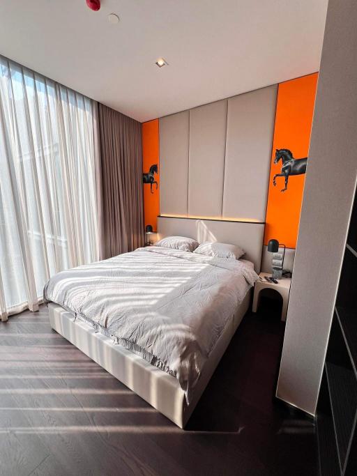 Modern bedroom with vibrant orange wall and artwork