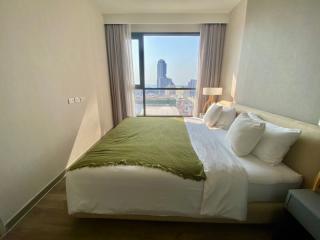 Modern bedroom with large window providing ample natural light and city view