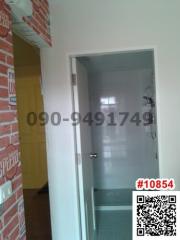 Narrow hallway in a home with a white door and brick wall accents