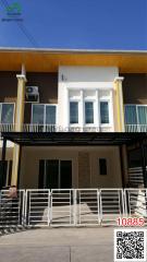 Exterior view of a modern two-story building with yellow accents and balcony