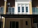 Exterior view of a modern two-story building with yellow accents and balcony