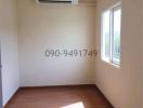 Empty bedroom with air conditioning unit and hardwood flooring