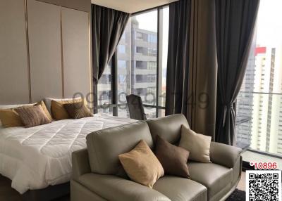 Modern bedroom with expansive windows and city view, featuring a king-size bed and plush seating area