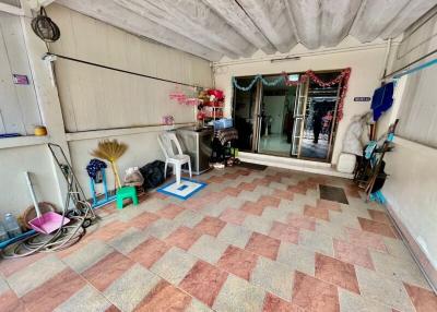 Spacious covered patio area with tiled flooring and various household items