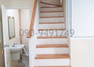 Wooden staircase with white balusters adjacent to a bathroom entrance in a residential home