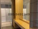 Modern hallway with built-in wooden desk and shelves, featuring a glass partition and ample lighting