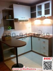 Compact modern kitchen with wooden countertop and white cabinetry