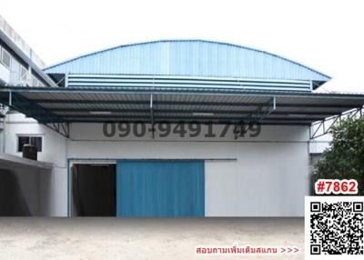 Spacious industrial building with blue sliding doors and a large sheltered area