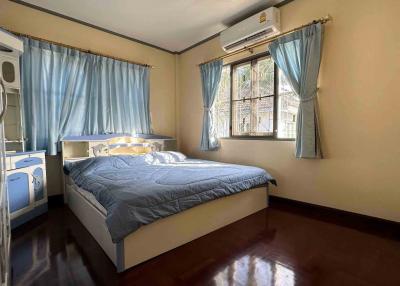 Cozy bedroom with wooden flooring, air conditioner, and large windows