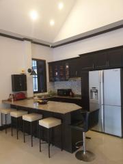 Modern kitchen interior with bar stools and well-equipped appliances