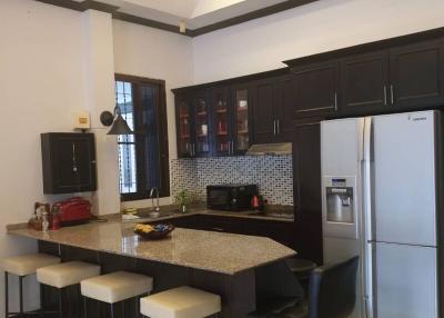 Modern kitchen interior with bar stools and well-equipped appliances