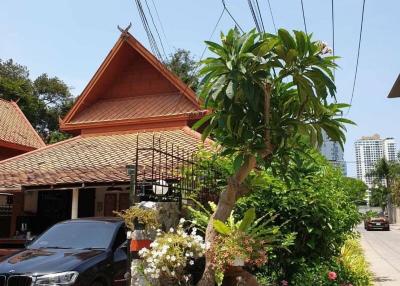 Traditional house exterior with a lush garden and a luxury car