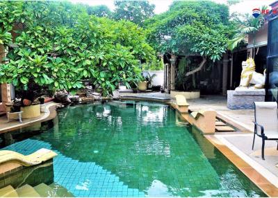 Lush tropical garden with a swimming pool and decorative statues