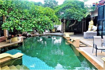 Lush tropical garden with a swimming pool and decorative statues