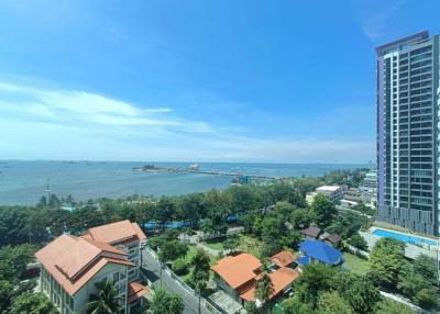 Panoramic view from a high-rise apartment balcony overlooking the ocean, with clear skies and surrounding buildings