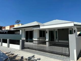 Modern single-story house with gray roofing and fenced yard