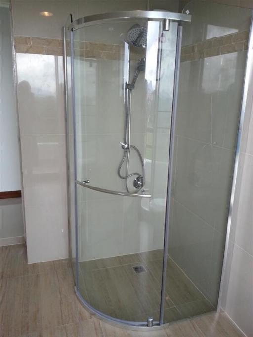 Modern glass-enclosed shower with tiled walls in bathroom